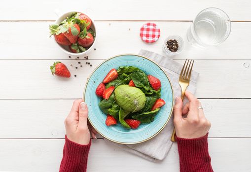 Healthy eating. Salad with strawberries, avocados, spinach on a white wooden background top view flat lay