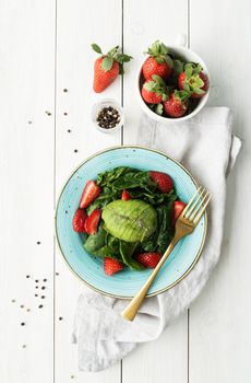 Healthy eating. Salad with strawberries, avocados, spinach on a white wooden background top view flat lay