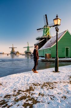 young man walked in the snow, snow covered windmill village in the Zaanse Schans Netherlands, historical wooden windmills in winter Zaanse Schans Holland during winter