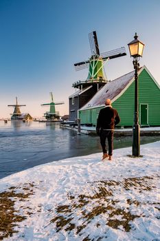 young man walked in the snow, snow covered windmill village in the Zaanse Schans Netherlands, historical wooden windmills in winter Zaanse Schans Holland during winter