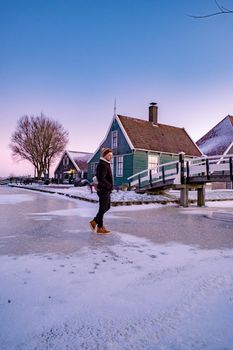 young man walked in the snow, snow covered windmill village in the Zaanse Schans Netherlands, historical wooden windmills in winter Zaanse Schans Holland during winter