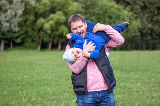 A man plays with his son on a green lawn. Live the emotions of the father and the son. Family.