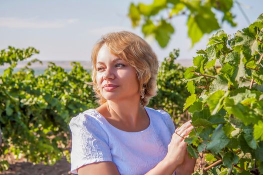 Portrait of a fair-haired young girl. A girl among the greenery of the vineyards. Portrait on a background of green foliage. Girl.  