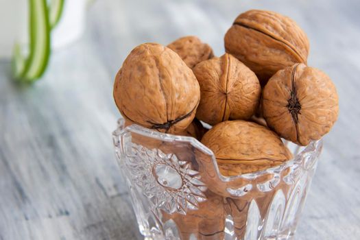 Walnuts on a painted background. Crystal bowl with nuts. Useful products. Walnuts.