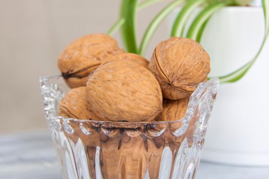 Walnuts on a painted background. Crystal bowl with nuts. Useful products. Walnuts.