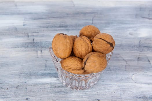 Walnuts in a shell on a painted background in a crystal vase. Healthy nuts. Walnuts. 