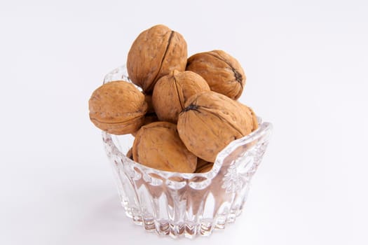 Walnuts in a shell on a white background in a crystal vase. Healthy nuts. Walnuts.