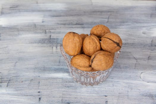 Walnuts in a shell on a painted background in a crystal vase. Healthy nuts. Walnuts.