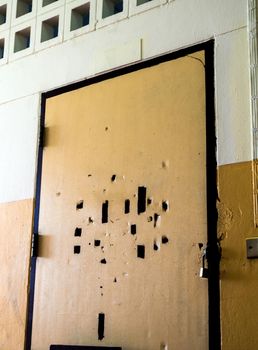 Many broken holes on the old classroom door are locked