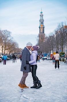 couple visit Amsterdam during Winter with people Ice skating on the canals in Amsterdam the Netherlands in winter, frozen canals in Amsterdam during winter. 