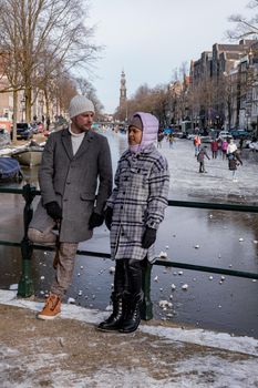 couple visit Amsterdam during Winter with people Ice skating on the canals in Amsterdam the Netherlands in winter, frozen canals in Amsterdam during winter. 