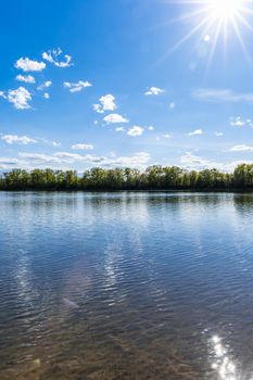 Vertical landscape of big Bajkal lake at sunny cloudy day at coast of peninsula with shining sun