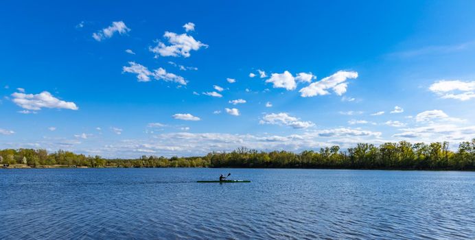 Man swimming on kayak on big Bajkal lake at cloudy day