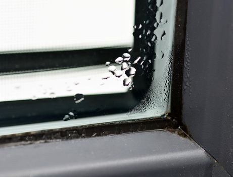 Closeup of the winter condensation on the inside of a window, insulation failure. A window glass covered with condensation drops.