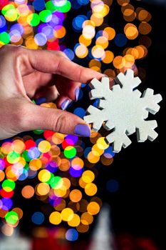 Holding Christmas snowflake decoration isolated on background with blurred lights. December season, Christmas composition.