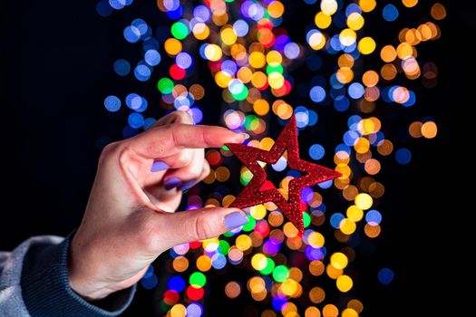 Holding Christmas glittery star decoration isolated on background with blurred lights. December season, Christmas composition.