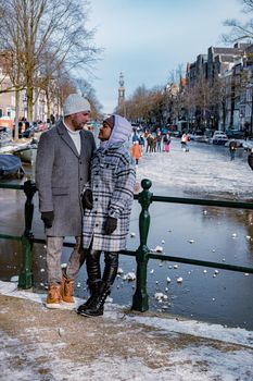 couple visit Amsterdam during Winter with people Ice skating on the canals in Amsterdam the Netherlands in winter, frozen canals in Amsterdam during winter. 