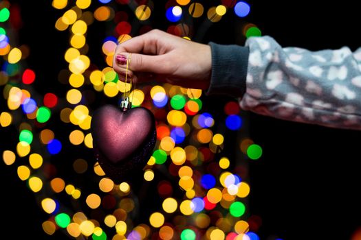 Woman's hands hold christmas decoration. Christmas and New Year holidays background, winter season with Christmas ornaments and blurred lights