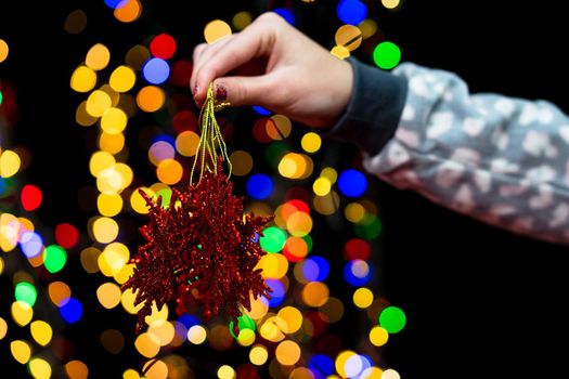 Woman's hands hold christmas decoration. Christmas and New Year holidays background, winter season with Christmas ornaments and blurred lights