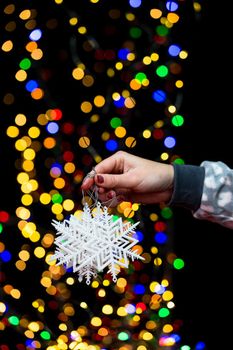 Woman's hands hold christmas decoration. Christmas and New Year holidays background, winter season with Christmas ornaments and blurred lights