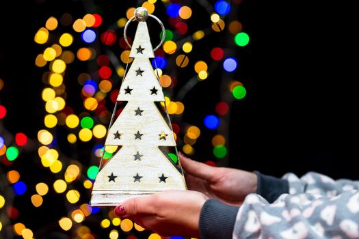 Woman's hands hold christmas decoration. Christmas and New Year holidays background, winter season with Christmas ornaments and blurred lights