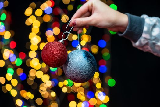 Woman's hands hold christmas decoration. Christmas and New Year holidays background, winter season with Christmas ornaments and blurred lights