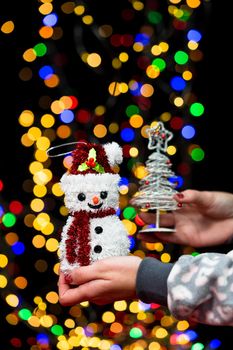 Woman's hands hold christmas decoration. Christmas and New Year holidays background, winter season with Christmas ornaments and blurred lights