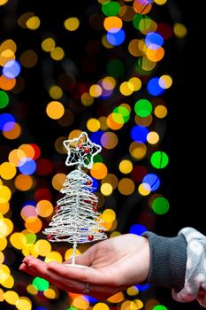 Woman's hands hold christmas decoration. Christmas and New Year holidays background, winter season with Christmas ornaments and blurred lights