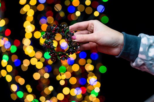 Woman's hands hold christmas decoration. Christmas and New Year holidays background, winter season with Christmas ornaments and blurred lights