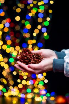 Woman's hands hold christmas decoration. Christmas and New Year holidays background, winter season with Christmas ornaments and blurred lights