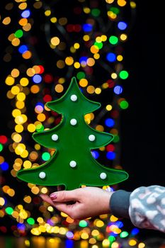 Woman's hands hold christmas decoration. Christmas and New Year holidays background, winter season with Christmas ornaments and blurred lights