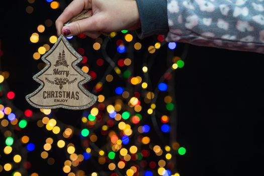 Woman's hands hold christmas decoration. Christmas and New Year holidays background, winter season with Christmas ornaments and blurred lights