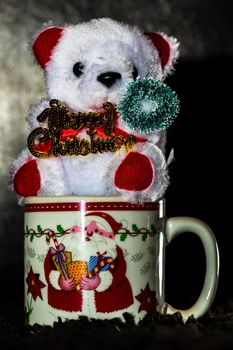 Decorated teddy bear in a Christmas cup isolated on black.  Bucharest, Romania, 2020.