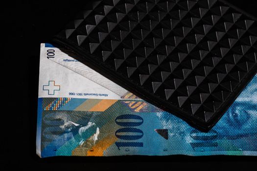 100 swiss franc banknote in a black wallet isolated.