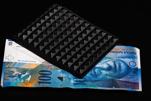 100 swiss franc banknote in a black wallet isolated.