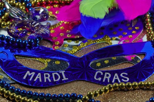 Mardi Gras carnival theme party masks with feathers and jewelry on textured gold surface abstract