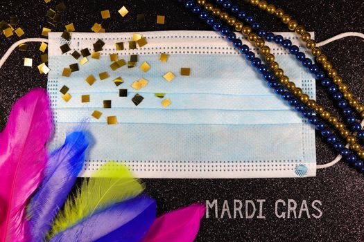 Mardi Gras carnival theme medical facemask with feathers and bead strings layout on textured black
