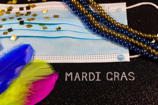 Mardi Gras carnival theme medical facemask with feathers and bead strings abstract on textured black