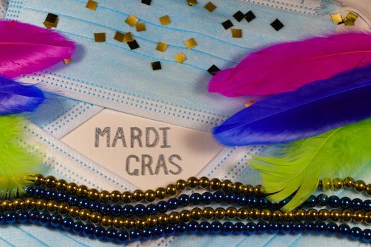 Mardi Gras carnival theme medical facemasks with bead strings and feathers layout on white