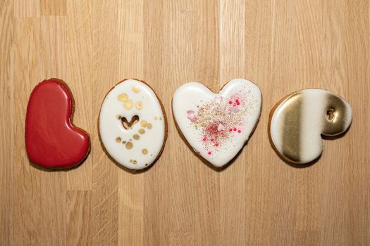 the word love from a beautiful ginger cookie on a wooden background. High quality photo