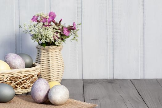 Easter composition - several eggs painted with natural dyes and wildflowers in a vase.