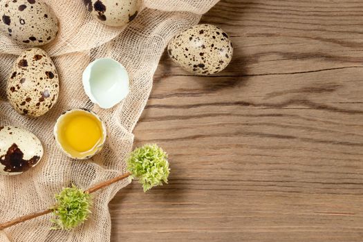 Composition of several quail eggs on decorative fabric on a wooden table, copy space, flatlay.