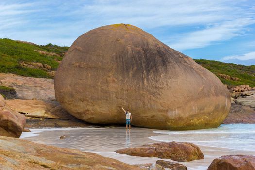 young caucasian man in front of a huge rock at Lucky Bay, Cape Le Grand National Park near Esperance