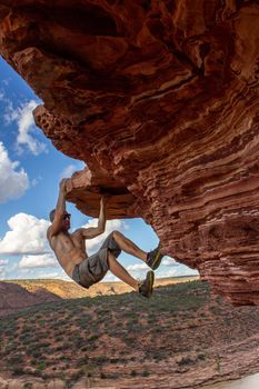 Carefree man is climbing on red sandstone rock of Nature's Window in Kalbarri National Park