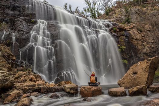 woman sitting on a rock in front of waterfall, Mackenzie Falls, The Grampians, Australia