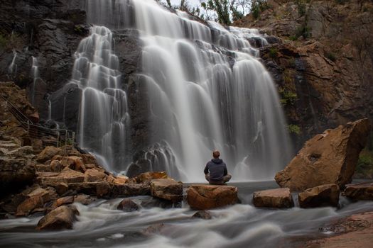 woman sitting on a rock in front of waterfall, Mackenzie Falls, The Grampians, Australia