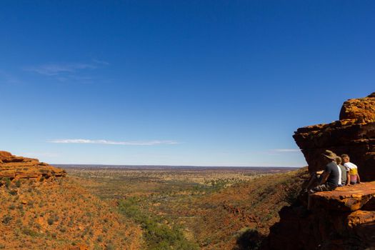 KINGS CANYON, AUSTRALIA May 5, 2015: young people enyoing view of the Kings Canyon and sitting on the edge of a cliff,, Watarrka National Park