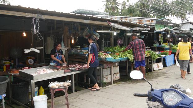 KOH SAMUI ISLAND, THAILAND - 10 JULY 2019: Food market for locals. Lively ranks with groceries. Typical daily life on the street in Asia. People go shopping for fruits vegetables, seafood and meat