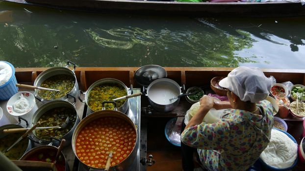 BANGKOK, THAILAND, 13 JULY 2019 Lat Mayom floating market. Traditional classic khlong river canal, local women in long-tail boat with oriental thai cusine assortment. Iconic asian street food selling