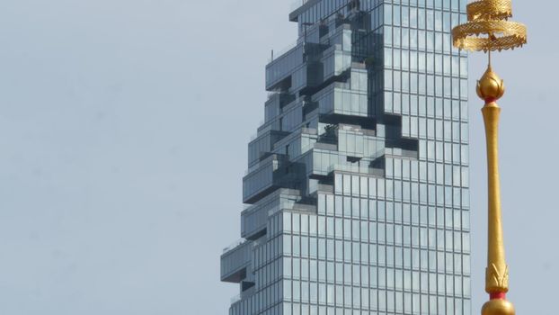 BANGKOK, THAILAND - 13 JULY, 2019: Conceptual contrast of oriental old traditional ancient temple and modern new futuristic Mahanakhon skyscraper. Classic buddhist wat compared to urban cityscape